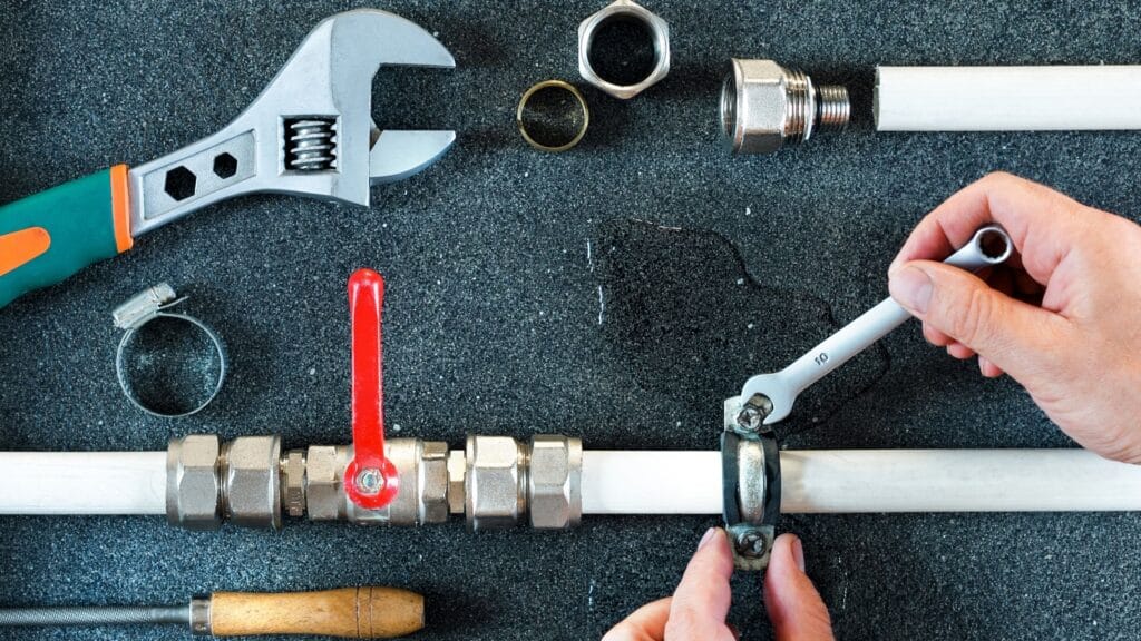 Plumber repairing a pipe valve with an adjustable wrench in Marietta