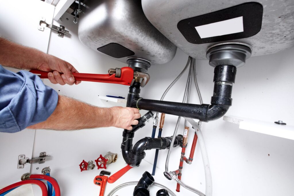 Plumber repairing drain pipes beneath a kitchen sink in Marietta