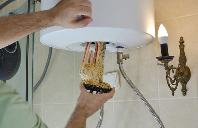 Technician removing mineral buildup from a water heater in Marietta