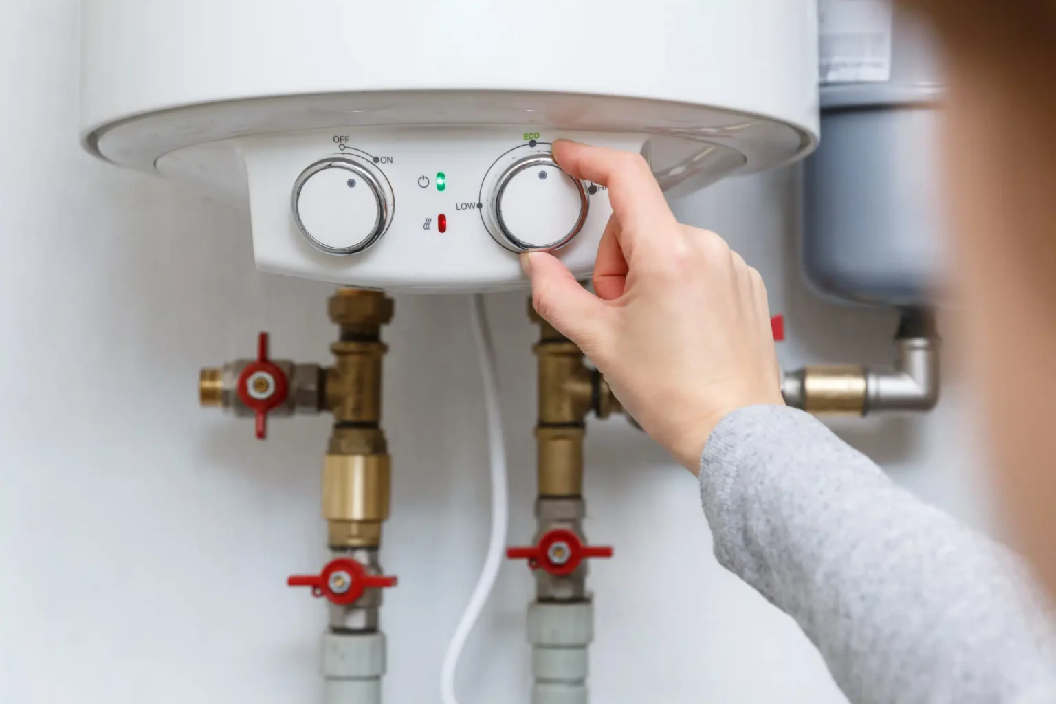 Homeowner adjusting the temperature controls on a water heater in Marietta